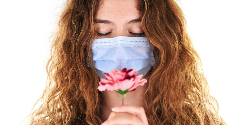 smelling flower with a mask